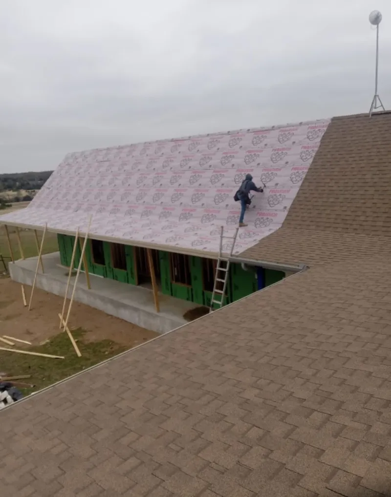 Worker preparing underlayment for a metal roof installation in Rothschild